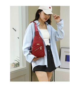 Detailed view of a red quilted nylon crossbody chest bag with gold-tone zipper details