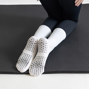 Close-up of white yoga socks with grey anti-slip silicone grips on black mat