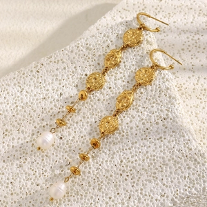 Macro detail of 18K gold-plated hammered discs and elegant pearl drop fringe earrings