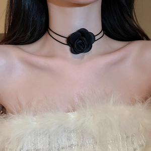 Close-up of elegant black fabric rose choker necklace on a neck with soft lighting