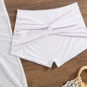 Detail view of white high-waisted bikini bottoms with elegant front knot design on wood