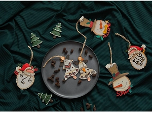 Flat lay of hand-painted wooden Christmas ornaments with snowmen on green fabric