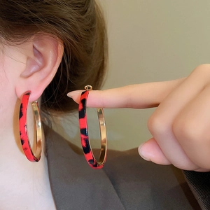 Detailed close-up of large leopard print hoop earrings with golden metal inner lining