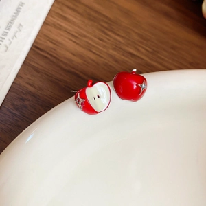 Macro detail of red apple stud earrings with enamel finish and crystal accents