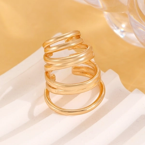 Close-up of golden multi-layer spiral ear cuff or ring on a white geometric pedestal