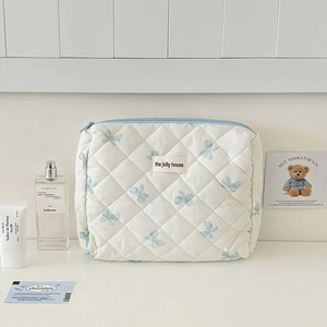 Detailed macro of the soft quilted makeup bag featuring blue bow patterns and zipper