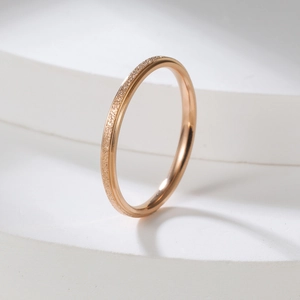 Detail of 2mm rose gold frosted stainless steel ring on a white geometric stand