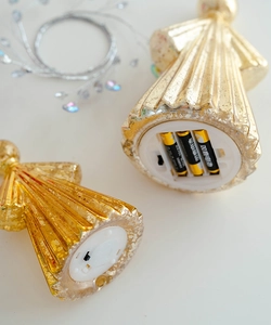 Detail of the golden glass angel ornament showing bottom battery compartment and switch