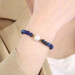Close-up of blue beaded bracelet with white pearl and gold accents on wrist