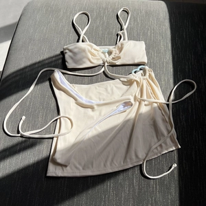 Detail of ribbed beige three-piece bikini set with ring buckle and side-tie sarong skirt