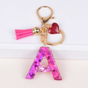 Detail of pink resin letter A keychain with glitter sequins, red heart and soft tassel