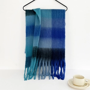 Detailed view of mohair plaid scarf with blue gradient patterns and soft fringe tassels