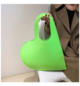 Close-up of heart-shaped felt handbag in neon green held by a model for styling