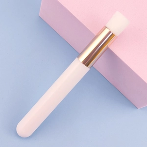 Detail view of a white lash cleansing brush with a golden ferrule on minimalist background