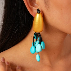 Detailed close-up of statement earrings with gold teardrop base and blue stone tassels