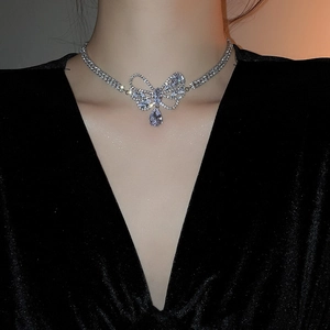 Detail of silver bow necklace with zircon waterdrop pendant worn on a model neck