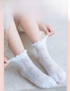 Detail of white mesh breathable baby socks with pink floral embroidery and ruffle cuffs