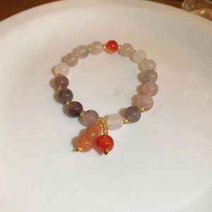Close-up of a colorful beaded bracelet with a gourd pendant in a ceramic dish