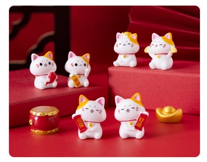 Detail view of lucky cat figurines with scrolls and golden ingots on red stands