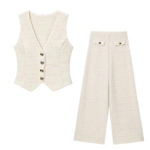 Détail du tissu en tweed crème avec des boutons dorés en forme de cœur sur le gilet