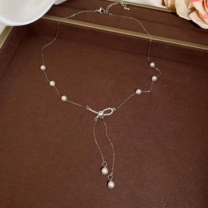 Detail of silver pearl necklace with rhinestone ring pendant on elegant brown tray