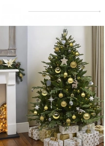 Detailed view of assorted gold and red Christmas baubles on a decorated tree with fireplace