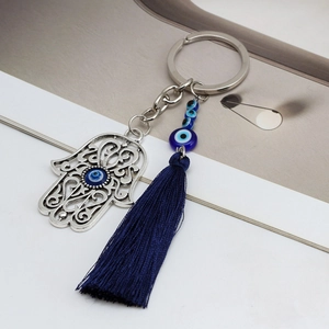 Macro shot of silver Hamsa Hand keychain with blue evil eye beads and silk tassel detail