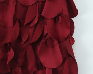 Détail du tissu à pétales rouge foncé sur l'ensemble haut dos nu et jupe à paillettes