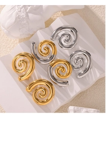 Boucles d'oreilles spirales artistiques dorées et argentées sur un socle blanc pur