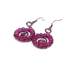 Detailed macro view of handmade wire-wrapped spiral earrings with purple beads and bronze hooks