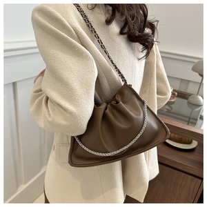 Detail of soft brown pleated leather shoulder bag with a sleek silver chain strap