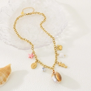 Détail d'un collier doré style plage avec pendentifs coquillage, hippocampe et étoile