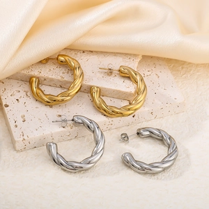 Twisted C-shape hollow hoop earrings in gold and silver finish on elegant silk background