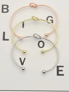 Detailed view of three open knot bracelets in rose gold, gold and silver finishes