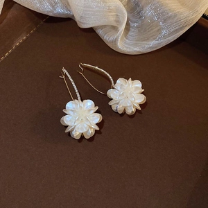 Detailed shot of floral tassel earrings with white resin petals and gold diamond accents