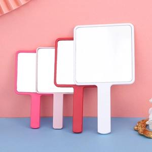 Square handheld mirrors in pink red and white colors on a colorful vanity surface