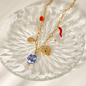 Detailed close-up of a gold necklace with heart, pearl, shell and floral ceramic charms