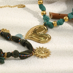 Detail of 18K gold stainless steel sun and heart pendants on woven bohemian cords