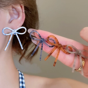 Détail de boucles d'oreilles nœuds en acrylique montrant la texture et le motif marbré
