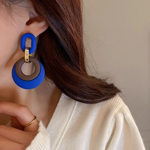 Detail shot of geometric Klein blue and brown chain drop earrings on a model