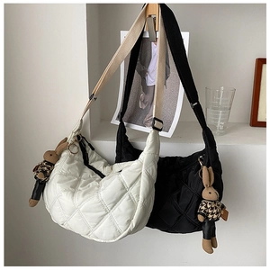 Close-up of quilted crescent shoulder bags with cute rabbit charms and wide straps