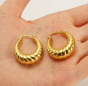 Detailed view of chunky gold-plated hollow hoop earrings with textured ribbed design