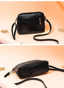 Detailed close-up view of black textured leather shoulder bag with secure zipper pocket.