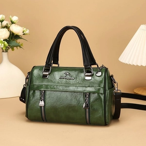 Retro dark green leather handbag with black handles and metal logo in warm interior setting