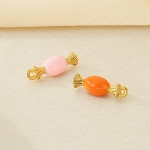 Macro shot of 18K gold plated candy-shaped charms in pink and orange enamel finish