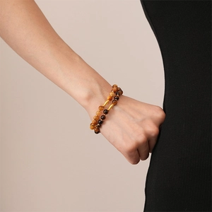 Detail of beaded tiger eye bracelet with golden accents on woman's wrist