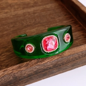 Makroaufnahme einer grünen Harz-Manschette mit rosa Kristallen und Diamantenbesatz