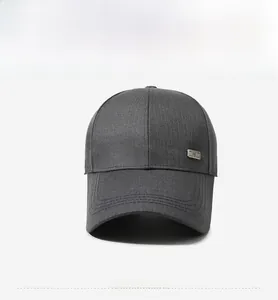 Front view of a dark grey twill baseball cap with a decorative metal logo plaque