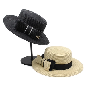 Detailed texture of flat top straw hat with bow and gold metal M letter charm