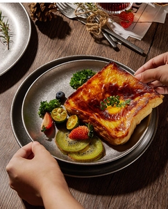 Close-up of vintage 304 stainless steel round plate with toast and fresh fruit slices